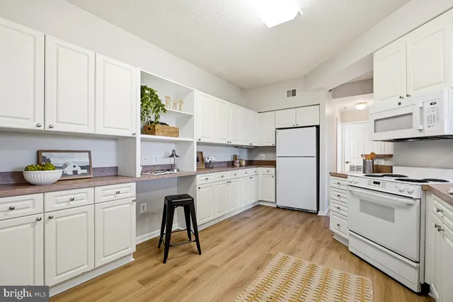 a kitchen with white cabinets white appliances and sink