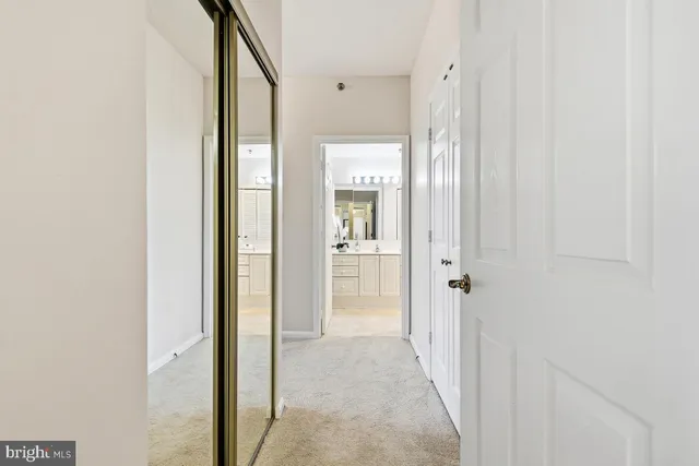 a view of a hallway with wooden floor and a bathroom