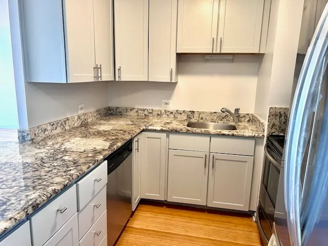 a kitchen with granite countertop white cabinets and white appliances
