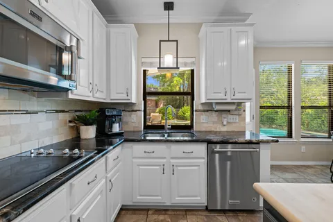 a kitchen with granite countertop a stove a sink and a microwave