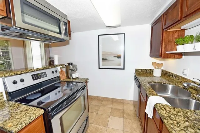 a kitchen with stainless steel appliances granite countertop a stove a sink and a microwave