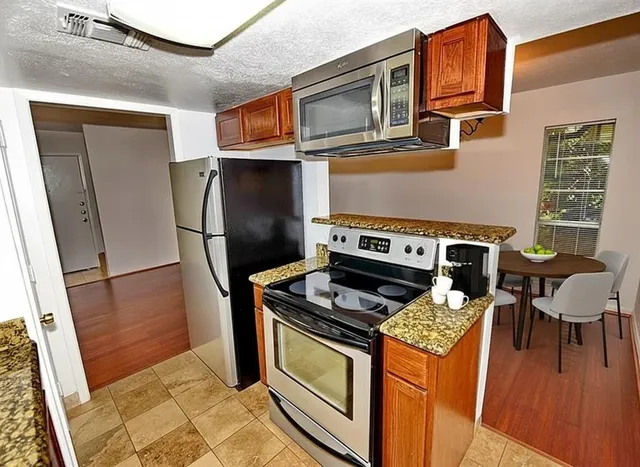 a kitchen with stainless steel appliances granite countertop a stove a refrigerator and a cabinets