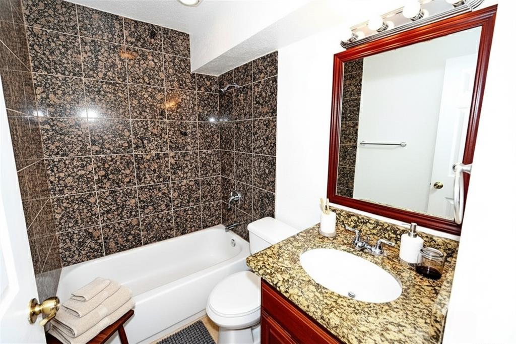 4317 Hartford Street, Unit 107 Dallas, TX 75219 - Photo 9 of 17 a bathroom with a granite countertop bathtub sink vanity mirror and toilet