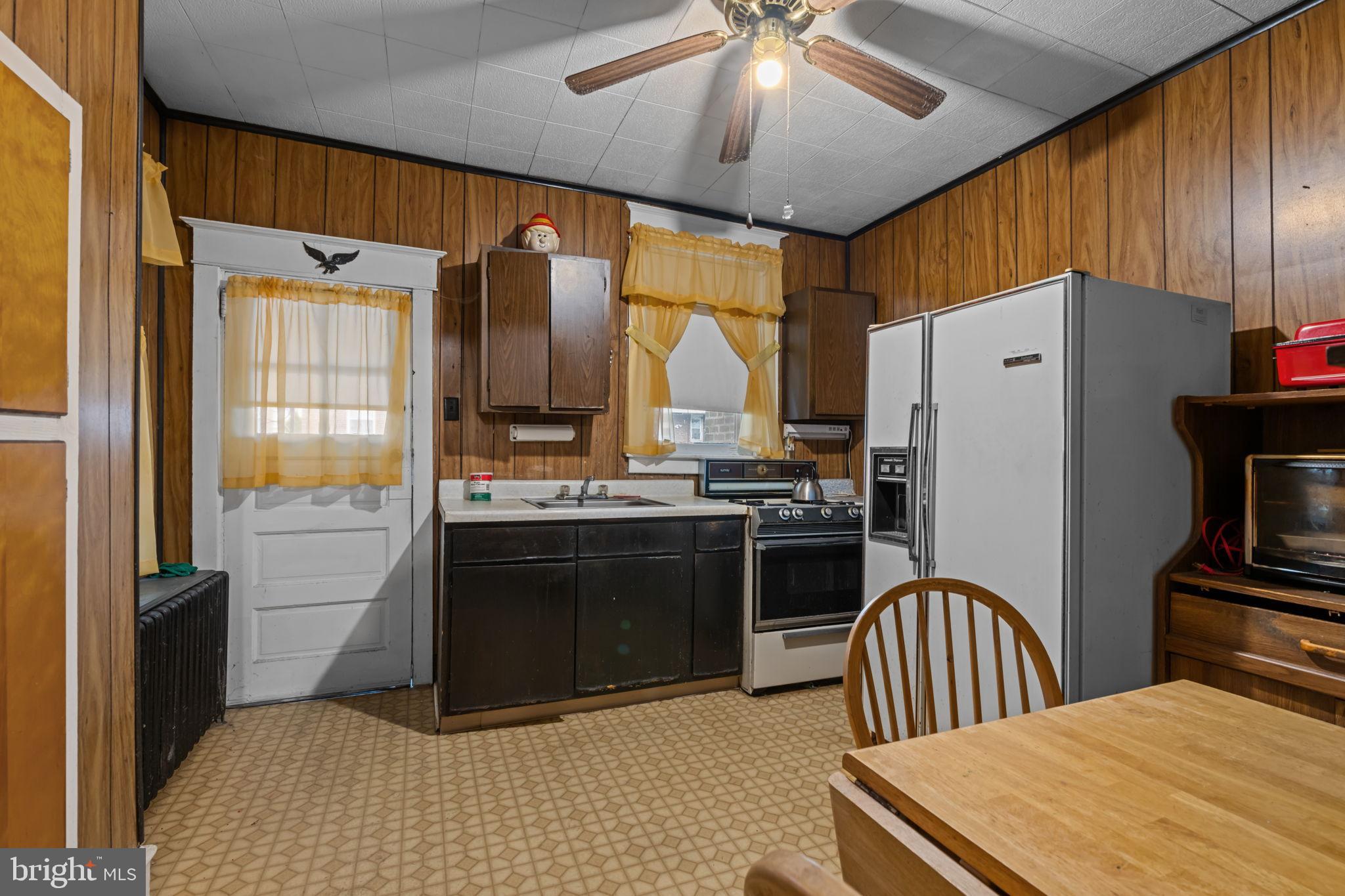 6520 Marsden Street Philadelphia, PA 19135 - Photo 10 of 26 a kitchen with stainless steel appliances granite countertop a refrigerator a sink dishwasher a stove and a dining table with wooden floor