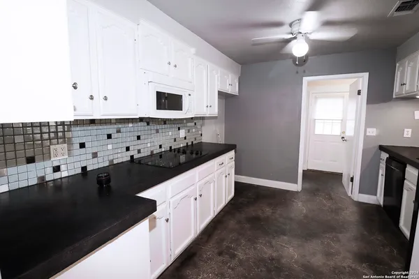 a kitchen with granite countertop a sink a stove and refrigerator