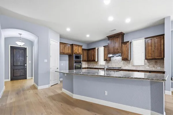 a view of an empty room with wooden floor and a fireplace