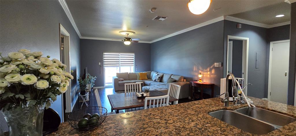 1100 West Trinity Mills Road, Unit 2045 Carrollton, TX 75006 - Photo 20 of 20 Kitchen with crown molding, ceiling fan, dark wood-style flooring, open floor plan, and dark stone counters