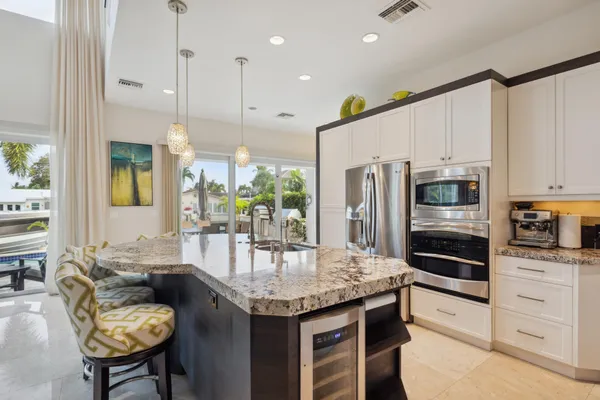 a kitchen with kitchen island granite countertop a table chairs stainless steel appliances and cabinets