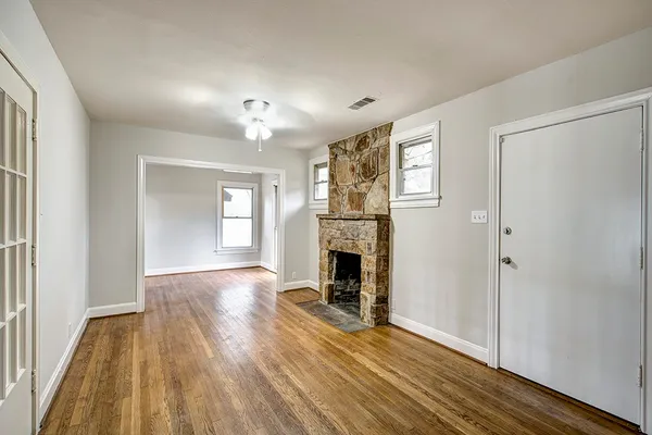 an empty room with wooden floor fireplace and windows