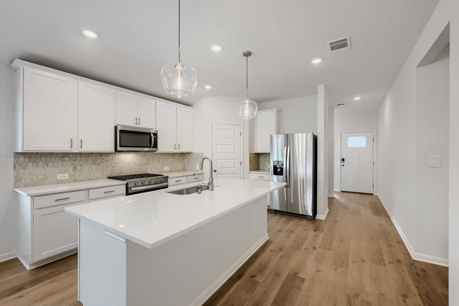 146 Diablo Rim Terrace Dripping Springs, TX 78620 - Photo 14 of 32 White cabinetry, stone counters, and a central island define this well-appointed culinary space.