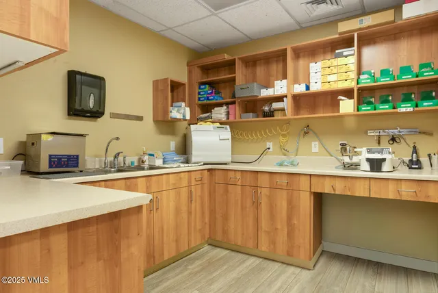a kitchen with a sink and a stove top oven with white cabinets