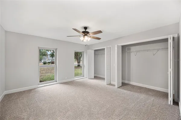 a view of a livingroom with a ceiling fan & windows