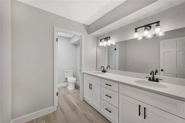 a spacious bathroom with a double vanity sink a large mirror a toilet and vanity