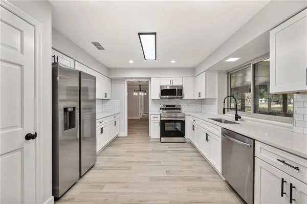 a large kitchen with stainless steel appliances lots of counter space and wooden floor