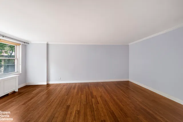 a view of an empty room with a window and wooden floor