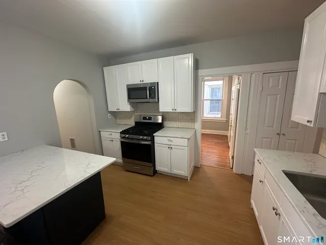 a kitchen with granite countertop a refrigerator stove and microwave