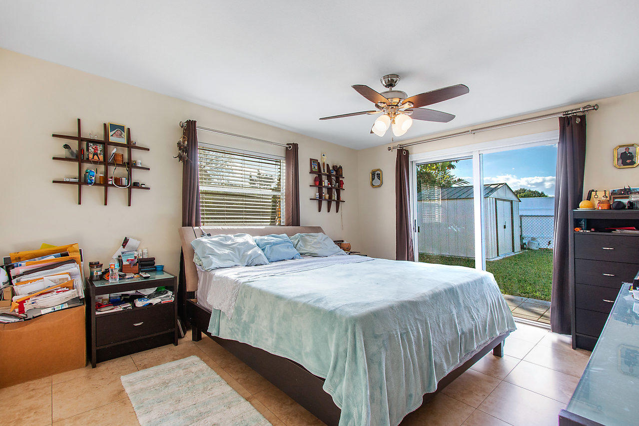 22045 Aquila Street Boca Raton, FL 33428 - Photo 14 of 24 a bedroom with a bed and a chandelier