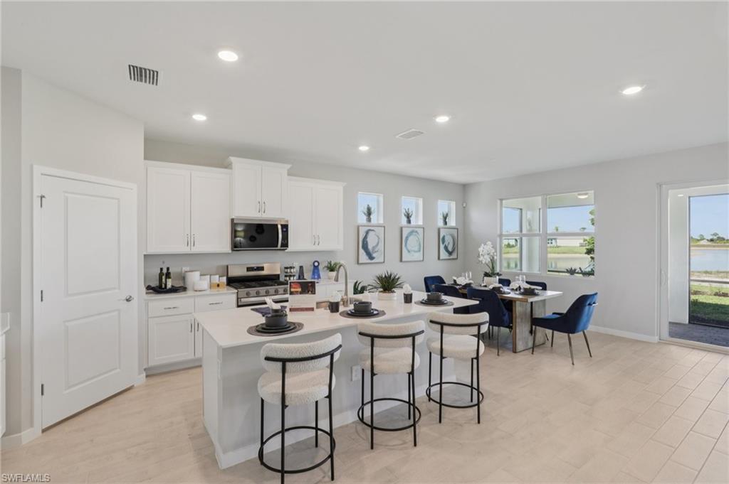 17899 Shade Tree Loop Punta Gorda, FL 33982 - Photo 8 of 47 a kitchen with stainless steel appliances kitchen island granite countertop a sink a stove a dining table and chairs