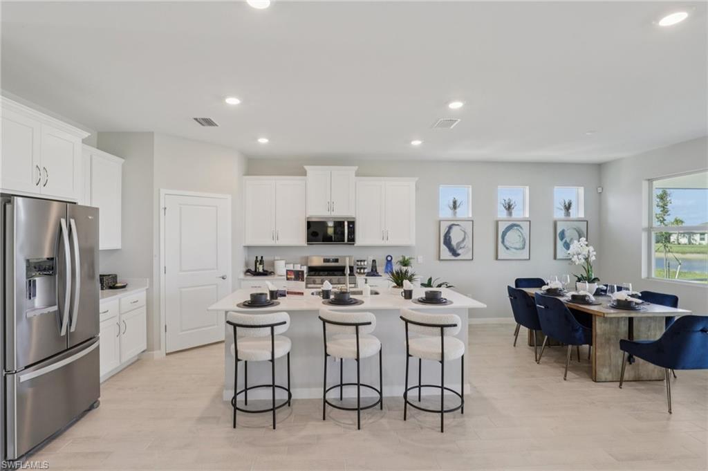 17899 Shade Tree Loop Punta Gorda, FL 33982 - Photo 9 of 47 a kitchen with stainless steel appliances kitchen island granite countertop a dining table chairs and a refrigerator