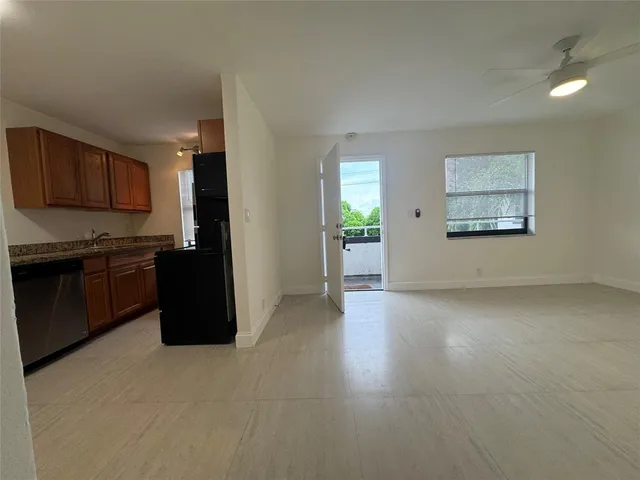 an empty room with kitchen view and a window
