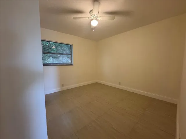 an empty room with a ceiling fan and a window