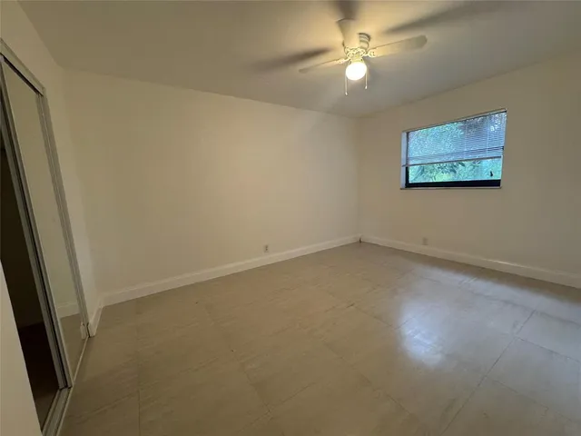 an empty room with a ceiling fan and a window