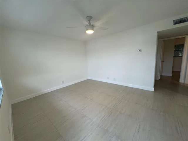an empty room with a ceiling fan and bathroom