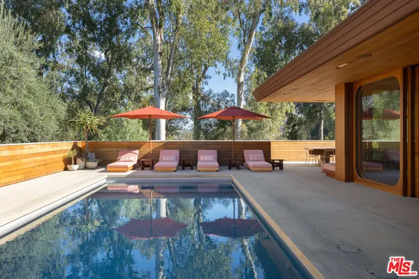 a view of a patio with couches table and chairs under an umbrella with a barbeque