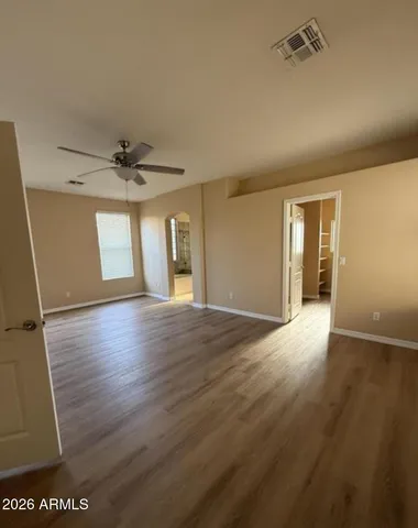 a view of an empty room with wooden floor and a window