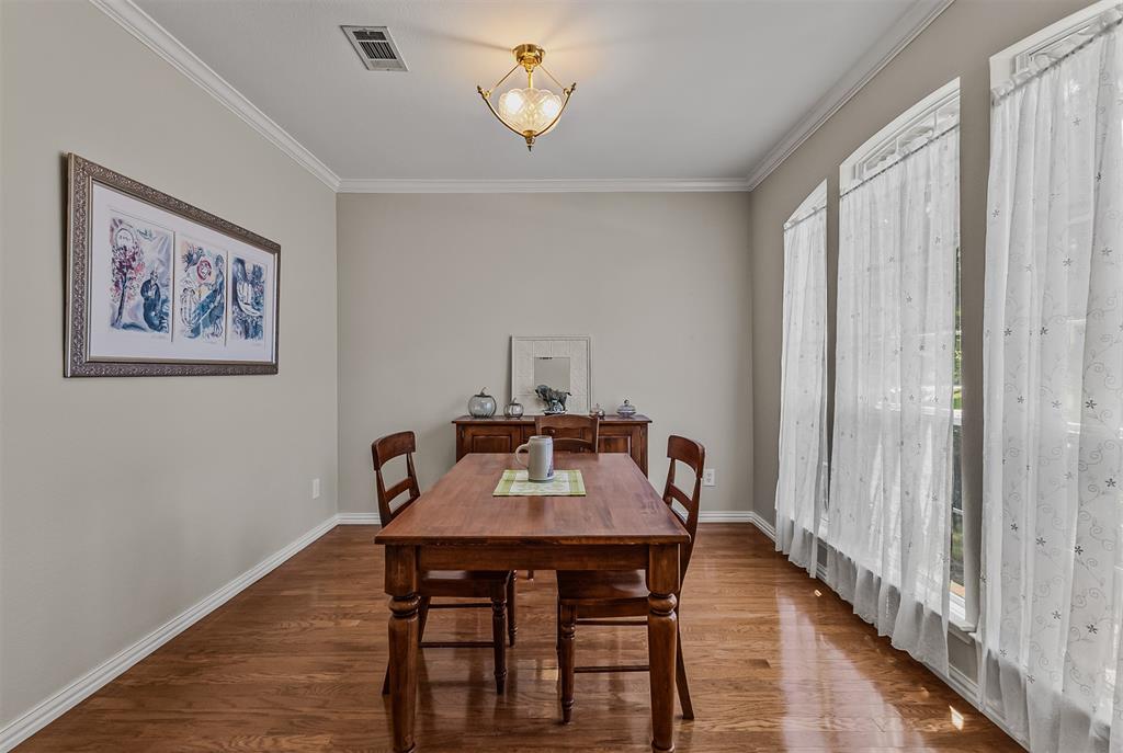 9301 Nottingham Court Rowlett, TX 75088 - Photo 12 of 39 Formal dining area featuring rich wood-finish flooring, tall arched windows, elegant crown molding, and a traditional ceiling light fixture