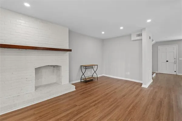 a view of empty room with wooden floor and fireplace