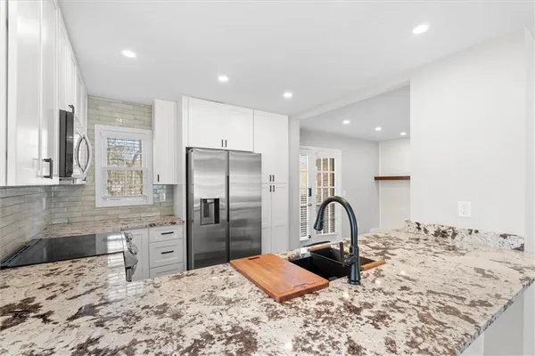 a kitchen with stainless steel appliances kitchen island granite countertop a refrigerator and a sink