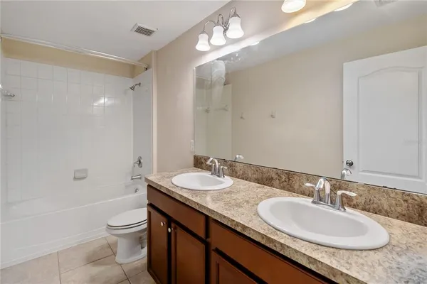 a bathroom with a granite countertop double vanity sink and a mirror