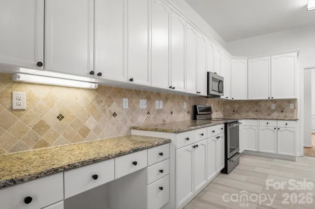 a kitchen with granite countertop white cabinets and sink