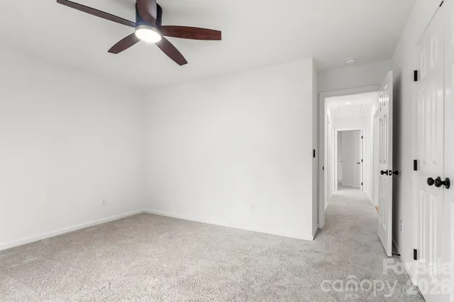 an empty room with a ceiling fan and carpet