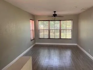 an empty room with wooden floor and windows