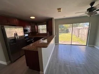 a open kitchen with stainless steel appliances granite countertop a refrigerator a sink a stove and island with wooden floor