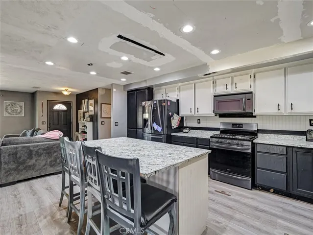 a kitchen with stainless steel appliances granite countertop a stove a refrigerator a kitchen island a table and chairs