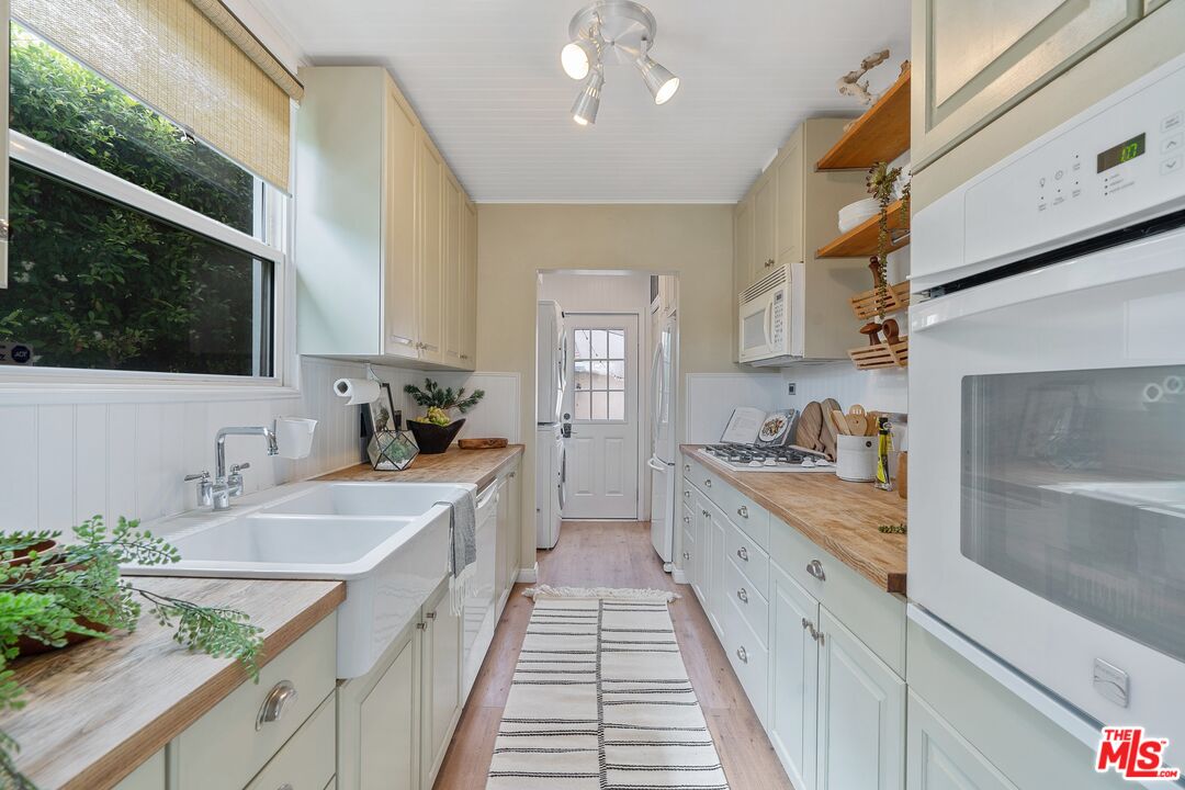 1585 Forest Avenue Pasadena, CA 91103 - Photo 9 of 28 a large white kitchen with a sink and dishwasher a stove top oven with wooden floor