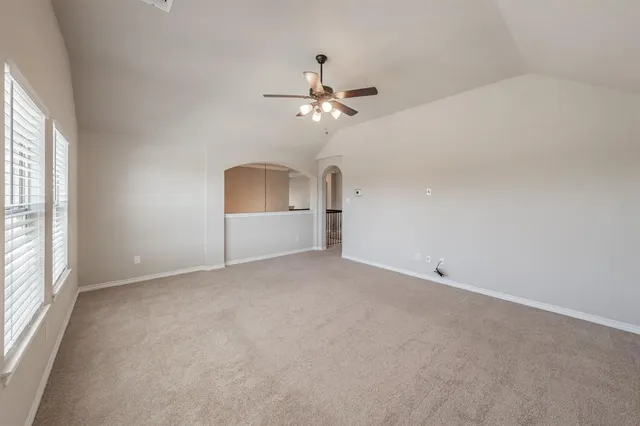 an empty room with chandelier fan and windows