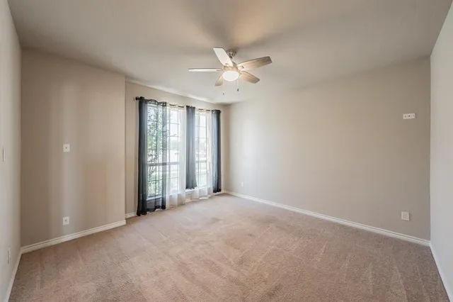 an empty room with windows and ceiling fan