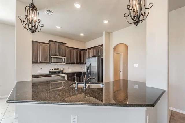 a kitchen with stainless steel appliances granite countertop a sink a stove counter space and cabinets
