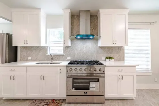 a kitchen with stainless steel appliances granite countertop a stove a sink and white cabinets