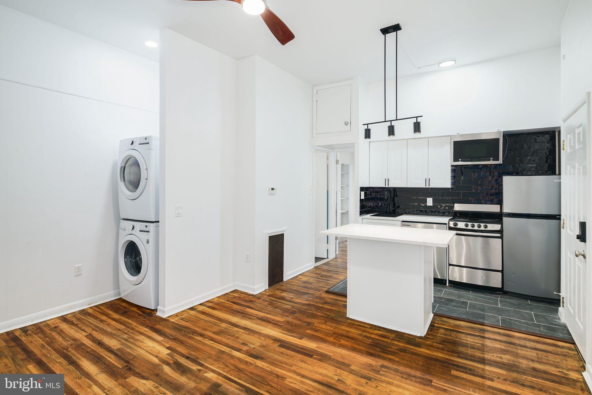 1024 Pine Street, Unit 2 Philadelphia, PA 19107 - Photo 1 of 7 a kitchen with stainless steel appliances kitchen island granite countertop a refrigerator a stove a sink and white cabinets with wooden floor