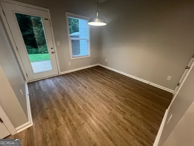 a view of kitchen and empty room with wooden floor