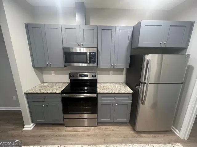a kitchen with kitchen island granite countertop a sink and a wooden floor
