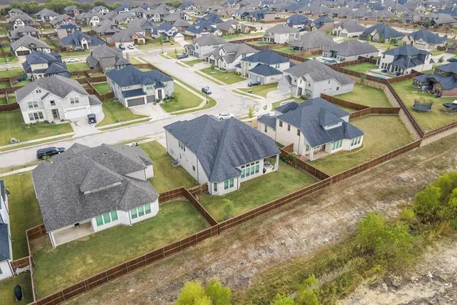 an aerial view of residential houses with outdoor space and trees