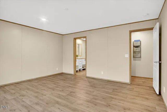 a view of an empty room with wooden floor and closet