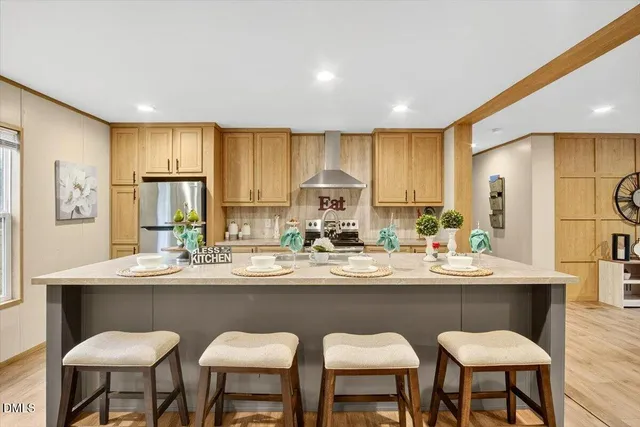 a kitchen with stainless steel appliances granite countertop a sink a stove a refrigerator cabinets and chairs