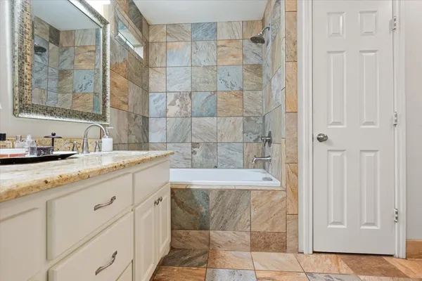 a bathroom with a granite countertop sink a mirror and a shower